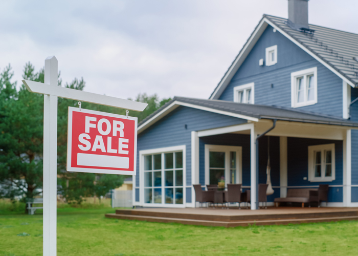 Red Home for Sale Sign in Frontyard of a Big Blue Stylish House