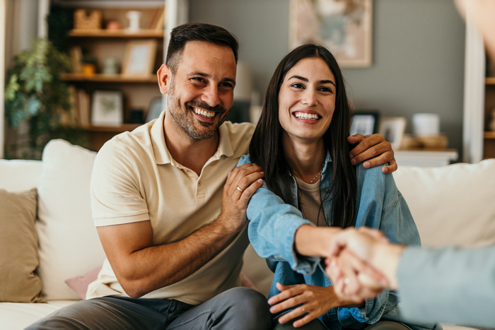 Happy couple shaking hands with financial advisor during meeting at home
